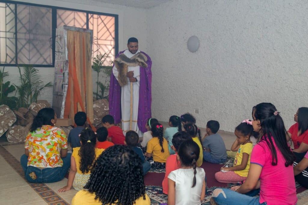 Sacerdote enseña a los niños durante una catequesis